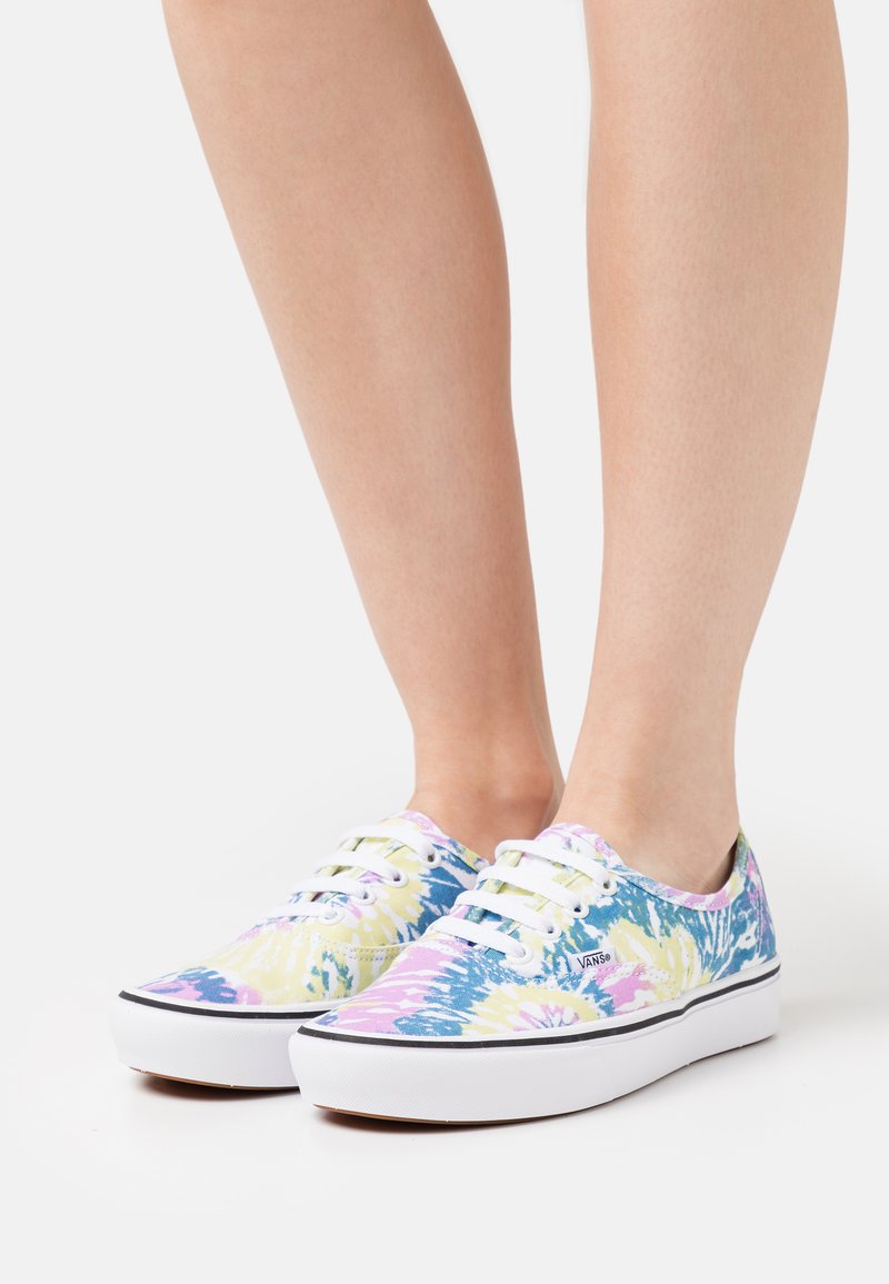 Canvas sneakers med et tie-dye mønster i pastell lilla, gul og blå. Har hvite snører og gummisåler med svart kant.