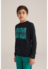 Čierna dlhá mikina s grafickým textom v tyrkysovej farbe "TOO COOL TO SLEEP" v skreslenom štýle; skombinovaná s tyrkysovými nohavicami.