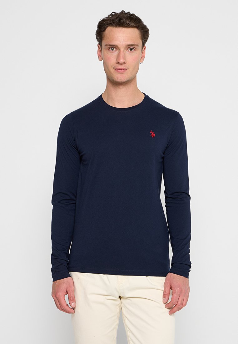 Marineblaues Langarmshirt aus einem glatten Stoff, mit rundem Ausschnitt und einem kleinen roten Logo auf der linken Brust.