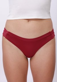 Κόκκινο εσώρουχο με δαντέλα, με λείο ύφασμα, χαμηλή μέση και λεπτές δαντελένιες λεπτομέρειες και στις δύο πλευρές.