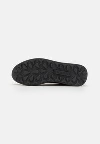 Black rubber shoe sole with textured tread pattern. Features the brand name "bugatti" embossed on the side for identification.