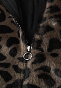 Leopard-print faux fur fabric with a black interior, featuring a silver zipper pull with a circular accent and a textured surface.