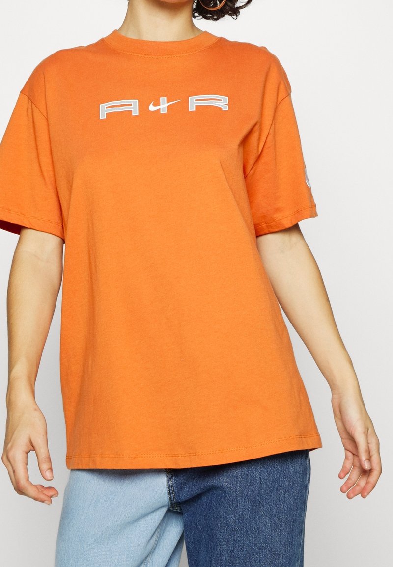 Oranžové bavlněné tričko s krátkými rukávy a kulatým výstřihem. Na hrudi má bílé nápisy "A1R". Uvolněný střih.