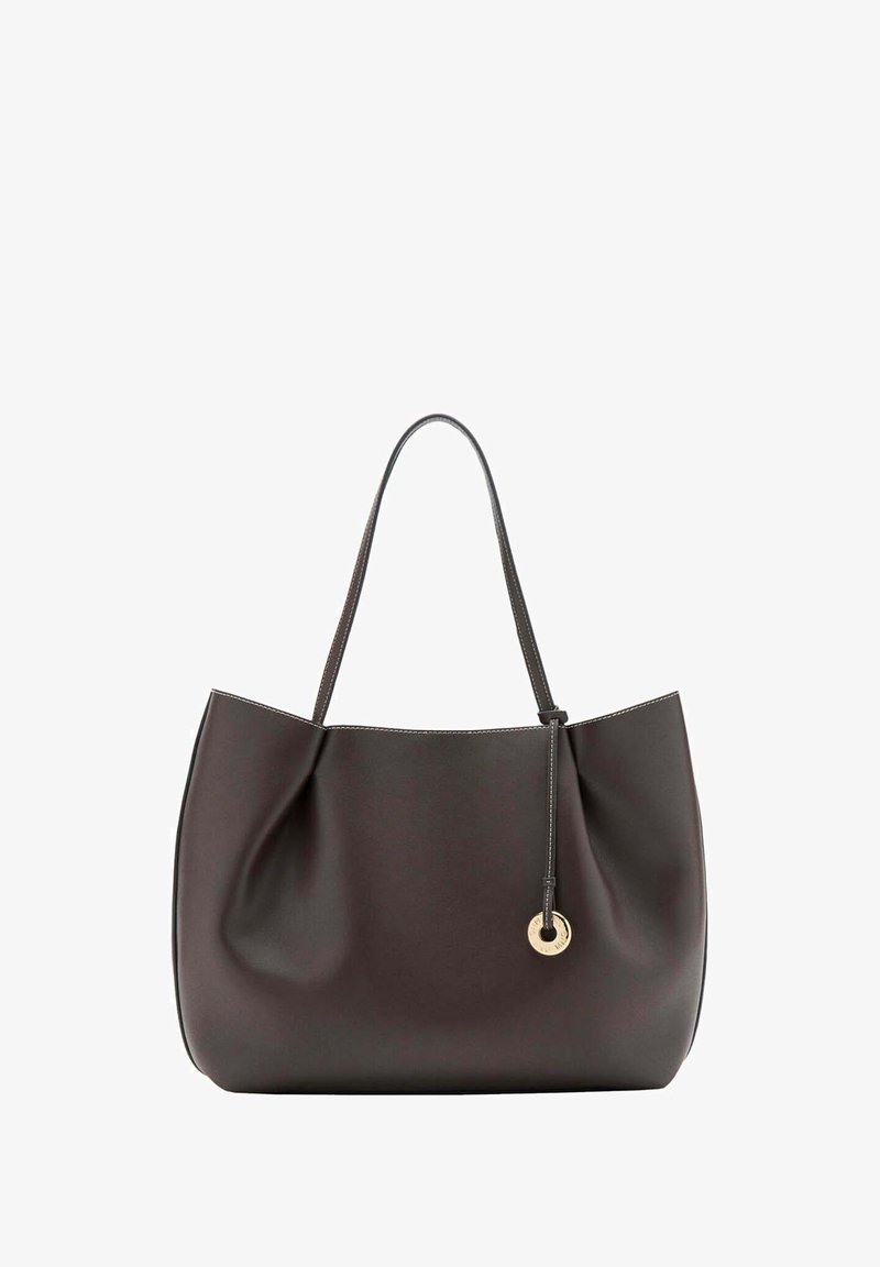 Sac cabas en cuir marron foncé avec une seule bandoulière et un charm rond doré suspendu à un cordon fin en cuir.