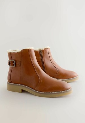 Ruske nahkasaapad nilkkamittaisilla, sivuvetoketjulla, solk yksityiskohdalla, tekokarvavuorella ja kevyillä kumipohjilla neutraalilla taustalla.