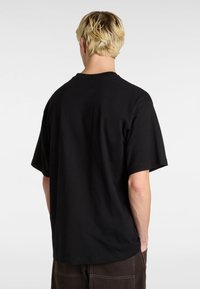 Černé oversized tričko vyrobené z bavlny, s kulatým výstřihem a krátkými rukávy. Hladký povrch bez viditelných vzorů nebo akcentů.