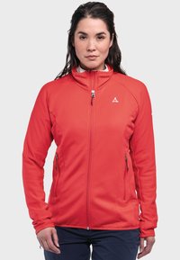 Rote Zip-Jacke mit hohem Kragen, geripptem Textil und seitlichen Taschen. Mit einem kleinen Logo auf der oberen linken Seite. Glattes Material.