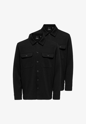 Due camicie nere a manica lunga con bottoni, colletti e tasche sul petto con bottoni frontali, mostrati sovrapposti su uno sfondo bianco.