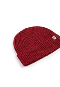 Red knitted beanie with a ribbed texture and cuffed edge, featuring a small branded tag.