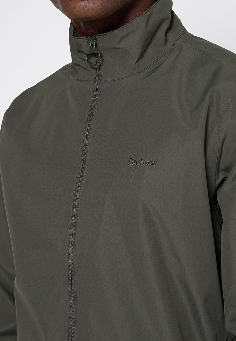 Giacca a vento verde oliva realizzata in materiale leggero, con colletto alto, zipper frontale e logo ricamato 'Barbour' sul petto.