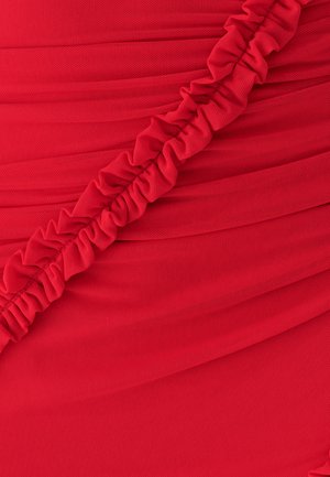 Red fabric with a textured surface features gathered sections and a ruffled accent, creating visual interest and depth in the design.
