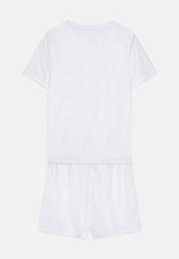 Bela majica s kratkimi rokavi in ujemajoče se kratke hlače iz gladkega, lahkega blaga z enostavno, brezšivno zasnovo.
