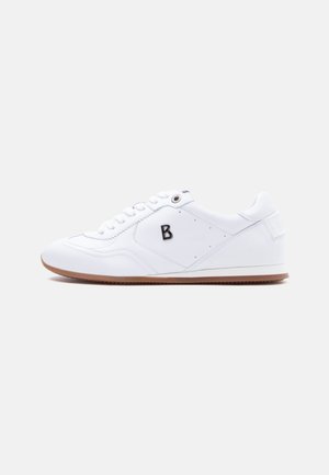 Witte lage sneaker met een bruine zool, witte veters en een zwarte letter "B" aan de zijkant tegen een effen lichte achtergrond.