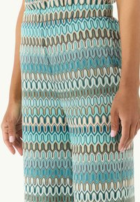 Pantalons à motifs dans des nuances de bleu, de turquoise et de marron présentant un design ondulé. Texture lisse avec une taille élastique et des poches latérales.