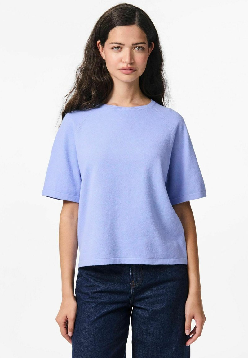 Gaiši zils īsās piedurknes tops no mīkstas, teksturētas auduma ar apaļu izgriezumu. Apvienots ar tumši ziliem džinsiem, tas nodrošina brīvu piegriezumu.