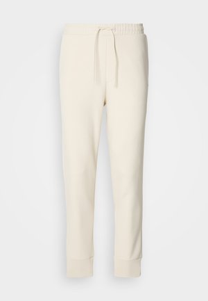 Off-white tapered sweatpants with elastic waistband, adjustable drawstring, and cuffed ankles on a plain white background.