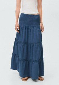 Blue tiered maxi skirt made of textured fabric, featuring a smocked waistband and ruffled accents for added detail.
