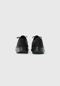 Pair of black athletic shoes with textured heel and loop pull tabs, viewed from the back on a plain light gray background.