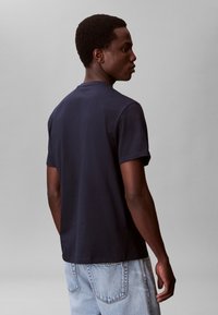 Marineblå bomuld t-shirt med korte ærmer, rund hals og en afslappet pasform, kombineret med lyseblå denimjeans. Enkel design uden synlige logoer.