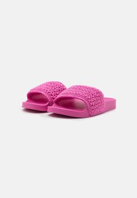 Sandales à glissière roses avec un dessus tissé texturé. Semelle plate et rembourrée pour un confort optimal. Design à bout ouvert arrondi pour un enfilage facile.