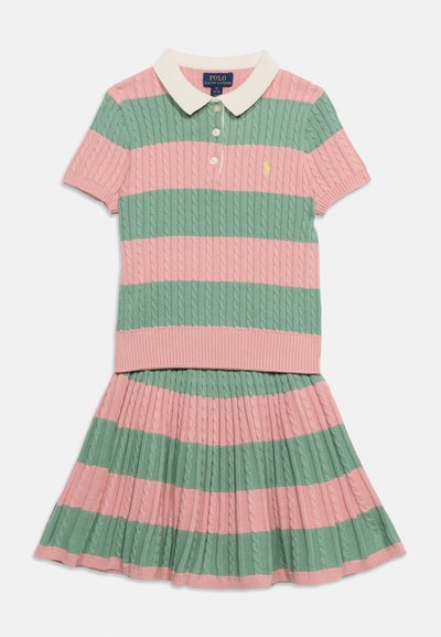 Πόλο με κοντά μανίκια και πλεκτή πλέξη, σετ με πλισέ φούστα με φαρδιές ροζ και πράσινες οριζόντιες ρίγες, λευκό γιακά και κουμπιά.