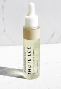 Duidelijke glazen druppelfles met een witte druppelaar en een beige etiket. De vloeistof binnenin is lichtgeel. De tekst is prominent weergegeven op het etiket.