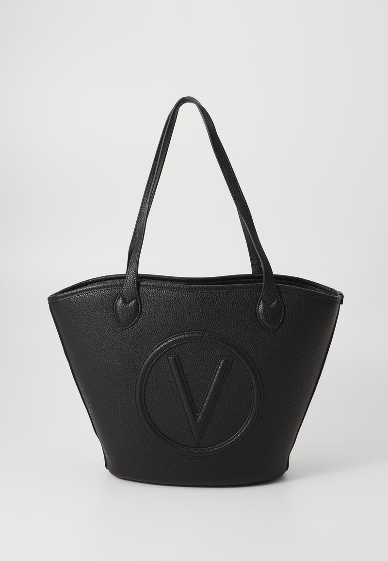 Black tote bag with a textured finish, featuring a circular embossed logo in the center, and two sturdy handles for easy carrying.