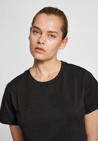 Sort bomulds t-shirt med rund halsudskæring og korte ærmer, der har en glat tekstur og et minimalistisk design.