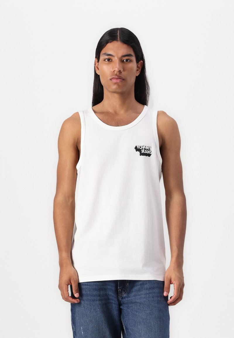 Fehér pamut ujjatlan felső kerek nyakkivágással, bal mellen fekete "Tommy Jeans" logóval. Kék farmernadrággal viselve.