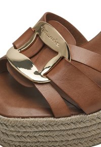 Sandale en cuir marron avec une boucle en ton doré, dotée d'une plateforme en jute tressé, de larges brides et d'une surface lisse et texturée.