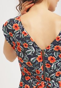 Květinové šaty v navy s živými oranžovými květy, s nízkým V-zadním výstřihem a skrytým zipem. Měkká látka s přiléhavým střihem.