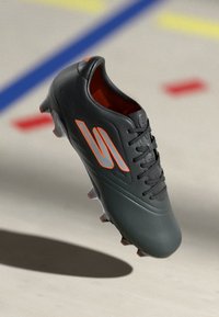 Black soccer cleat with orange accents, featuring a smooth synthetic upper, lace closure, and molded studs for traction on field surfaces.