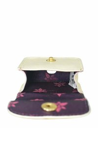 Witte leren portemonnee met een gouden drukknoopsluiting. Interieur van donkerpaarse stof versierd met roze bloemmotieven. Compact ontwerp.
