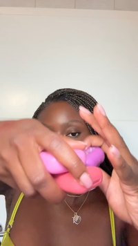 Tre dischi rotondi, colorati e simili al silicone, in rosa, viola e lavanda, tenuti tra le dita su uno sfondo chiaro.