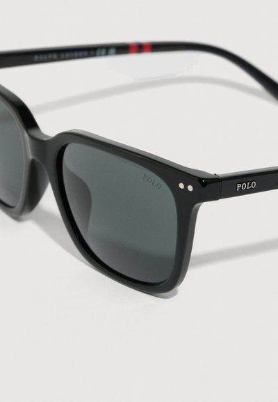Ochelari de soare din plastic negru cu lentile gri, având o formă rectangulară, finisaj lucios și mici accente albe pe laturi.
