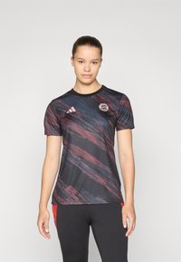 Zwarte sportshirt met korte mouwen, voorzien van abstracte patronen in rood en blauw, inclusief een Adidas-logo en een cirkelvormig embleem op de linkerborst.