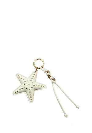 Portachiavi in pelle bianca a forma di stella con borchie dorate e cordino bianco annodato attaccato a un anello portachiavi dorato.