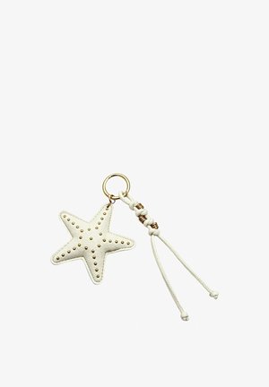 Portachiavi in pelle bianca a forma di stella con borchie dorate e cordino bianco annodato attaccato a un anello portachiavi dorato.