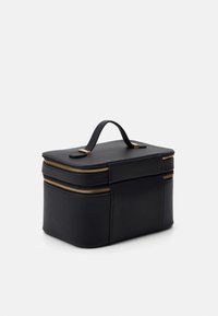 Bolso de cosméticos de cuero negro con dos cremalleras doradas, un asa superior y un diseño rectangular. Textura suave sin patrones o acentos visibles.