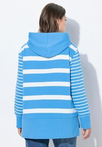 Hoodie blu a righe con cappuccio, caratterizzato da righe bianche alternate, una vestibilità rilassata e polsini e fondo a costine. Tessuto in cotone morbido e casual.