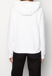 White hooded sweatshirt with a relaxed fit, featuring ribbed cuffs and waistband, smooth texture, and a minimalistic design.