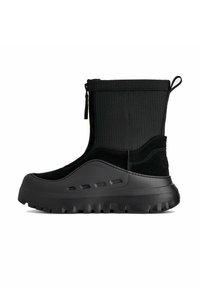 Stivaletto nero alla caviglia con tomaia in tessuto texturizzato, dettagli in camoscio, punta arrotondata e suola spessa in gomma con tasselli pronunciati.