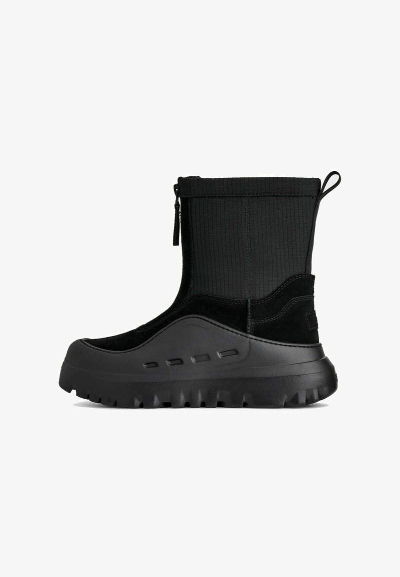 Stivaletto nero alla caviglia con tomaia in tessuto texturizzato, dettagli in camoscio, punta arrotondata e suola spessa in gomma con tasselli pronunciati.