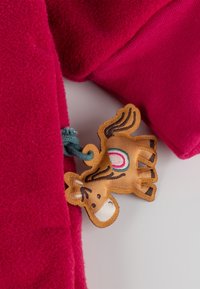 Fuchsia-farbener Fleeceartikel mit einem dekorativen braunen Pferdetag, der bunte Akzente und eine blaue Schnur aufweist, die am Stoff befestigt ist.