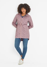 Lightweight pink raincoat with abstract pattern, full front zipper, adjustable hood, and waist cinch, paired with blue jeans and white sneakers.