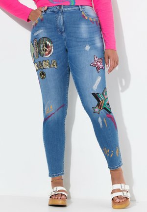 Blaue Skinny-Jeans aus Denim mit bunten gestickten Aufnähern, Paillettenbeschriftung und Farbspritzern. Modischer Schnitt mit verkürztem Saum.