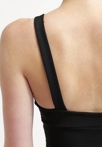 Schwarzes, geripptes Tanktop mit breiten Trägern, das eine glatte Textur und eine figurbetonte Passform aufweist, wobei eine Nahaufnahme des Rückens und des Schulterbereichs gezeigt wird.