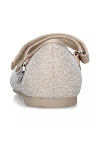 Scarpe bianche, testurizzate, con suola piatta, dotate di una cinghia e di un piccolo ciondolo decorativo sul retro. Il materiale scintillante aggiunge interesse visivo.