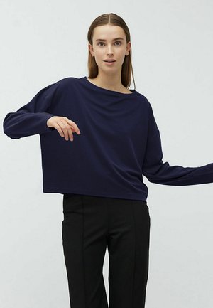 Navy blue, oversized long-sleeve top with a wide neckline and soft texture, paired with black tailored pants.
