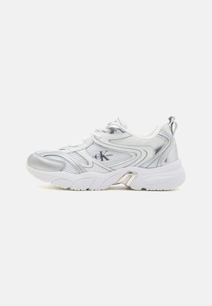 Białe i srebrne sportowe sneakersy z teksturowaną górną częścią z siatki, wyściełanym kołnierzem i masywną podeszwą. Posiadają szczegóły z logo oraz metaliczne akcenty.